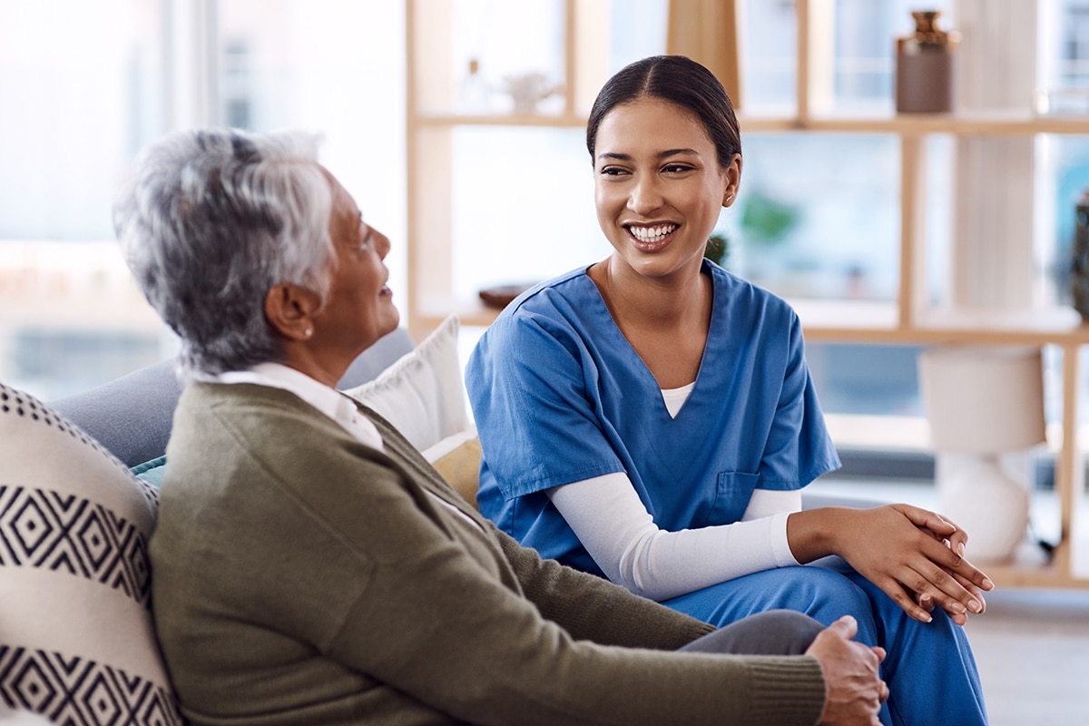 Nurse speaking with home care patient on couch