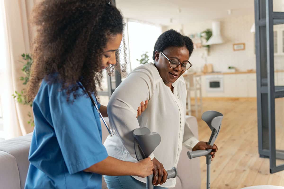 Home nurse helping patient stand up