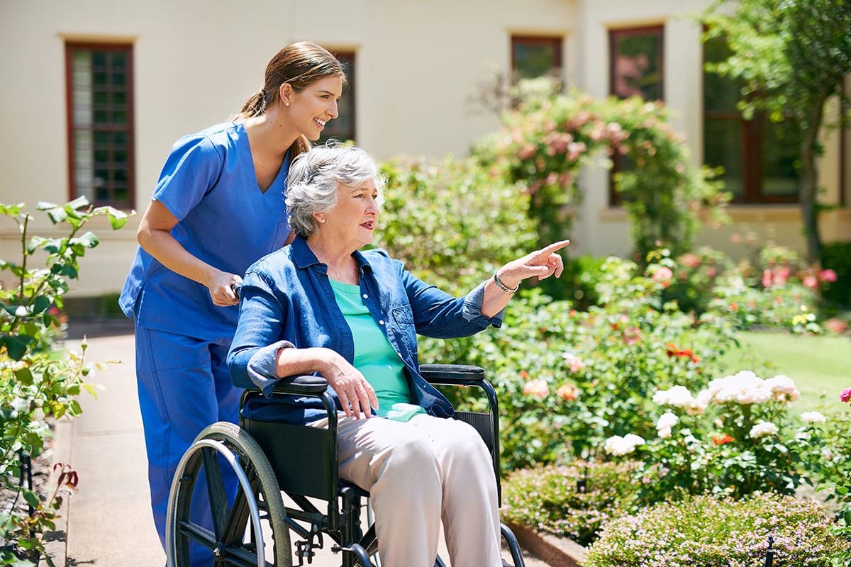 Home nurse walking through garden with client