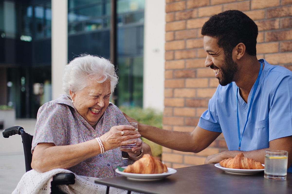 Caregiver having breakfast with his client at cafe.