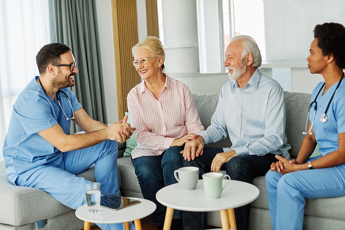 Home nurses speaking with elderly couple