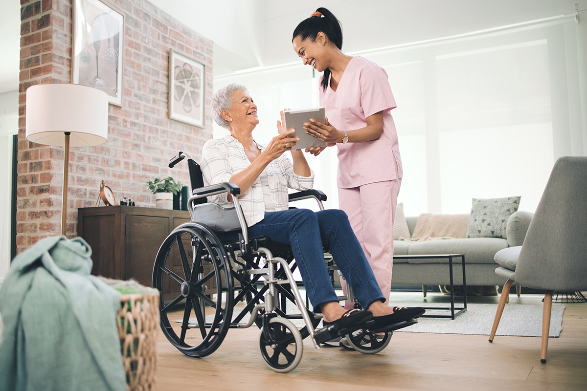 Home nurse smiling at patient while holding tablet