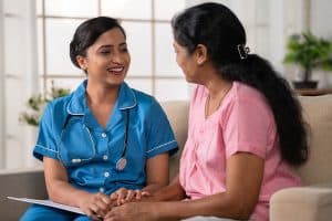 nurse sitting on the couch with a home care patient and talking