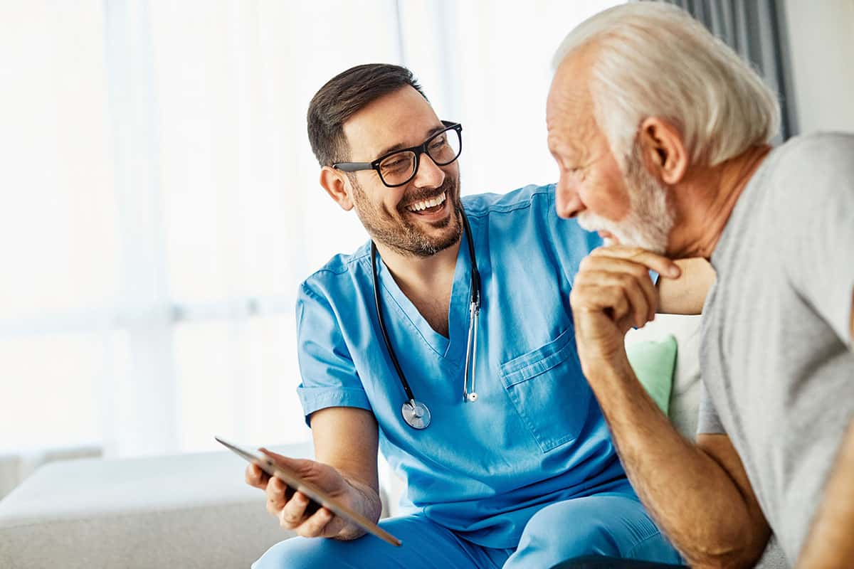 home nurse showing a patient a tablet while laughing together