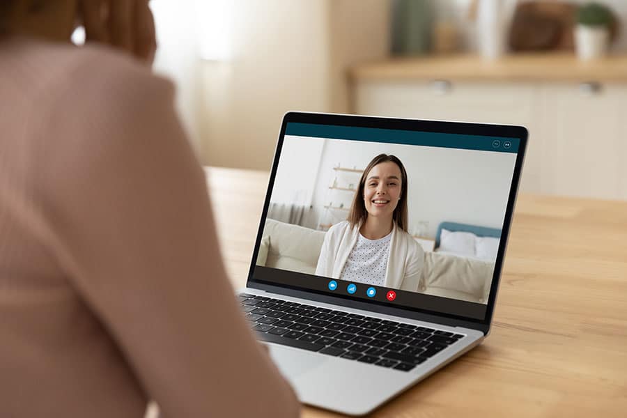 Person receiving software demo over video call on laptop