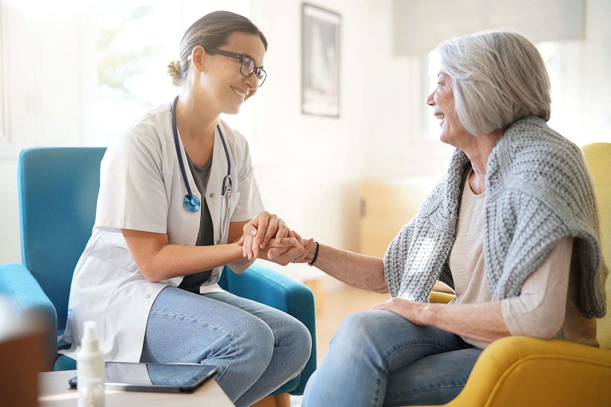 Home care professional reassuring older woman during home visit