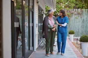 Homecare nurse walking with patient outside of their home