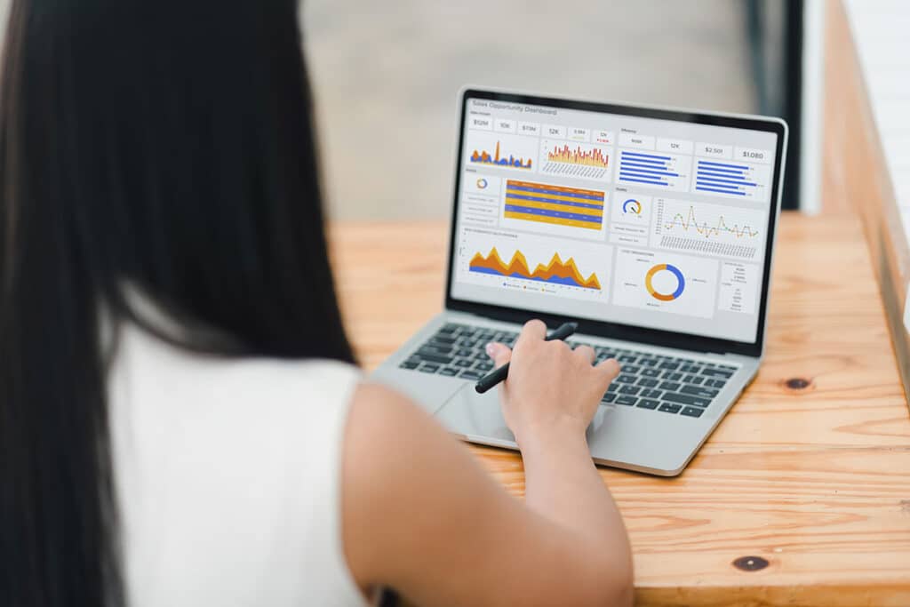 Businesswoman or an accountant team are analyzing data charts, graphs, and a dashboard on a laptop screen in order to prepare a statistical report
