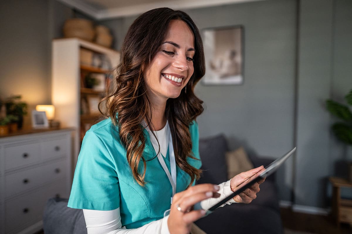 Smiling home care nurse using digital tablet
