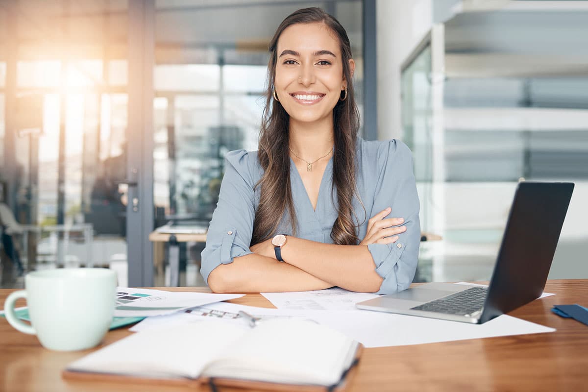 Business woman smiling at desk in office with laptop
