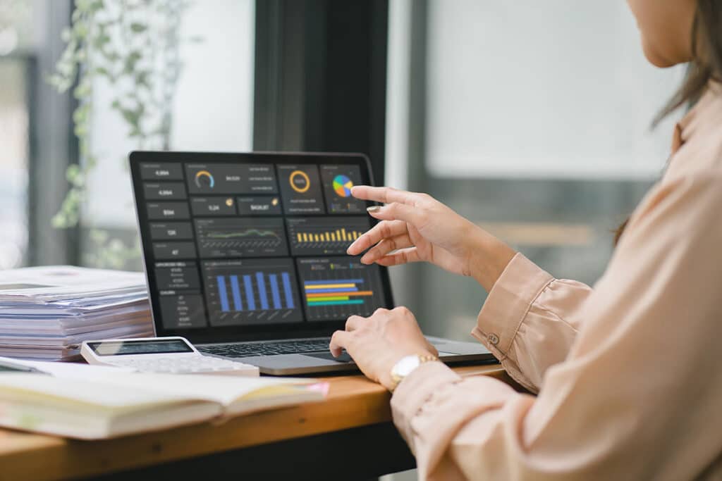 The female analyst utilizes a computer and a dashboard for business data analyze and a data management system with KPI.
