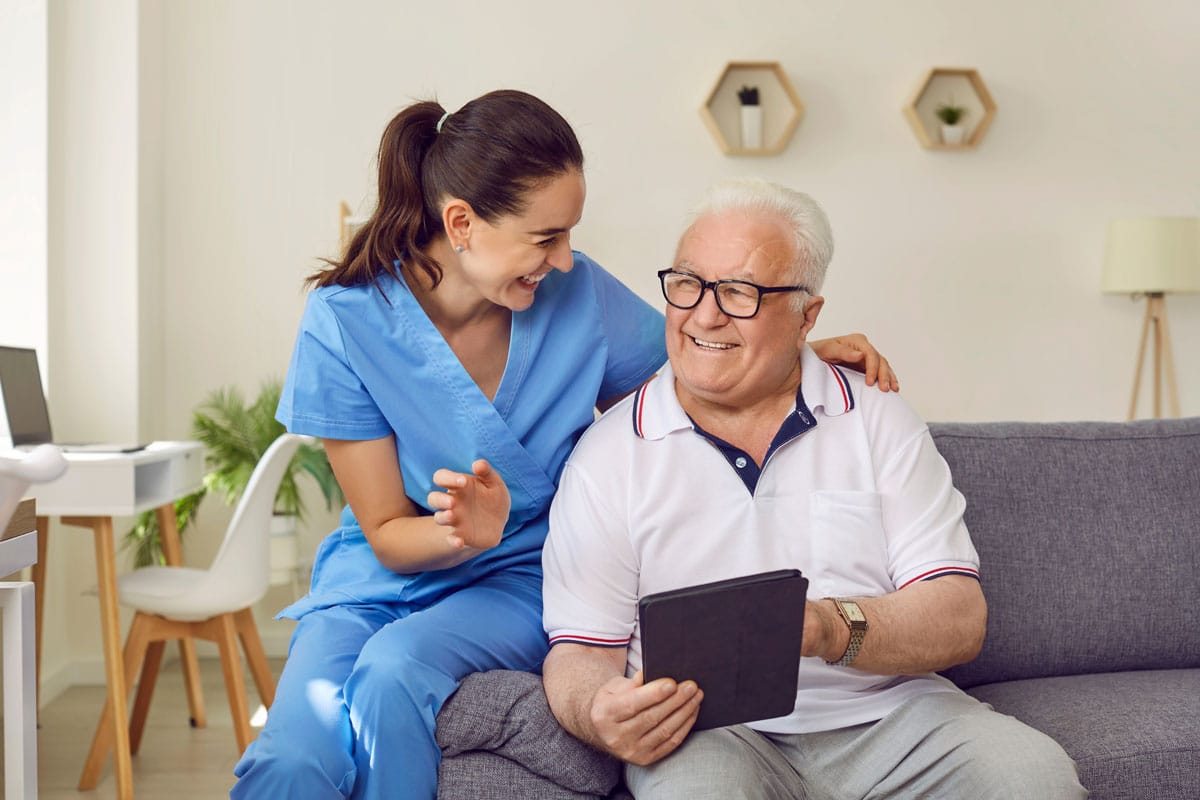 nurse-helping-elderly-gentleman-with-a-tablet-and-smiling
